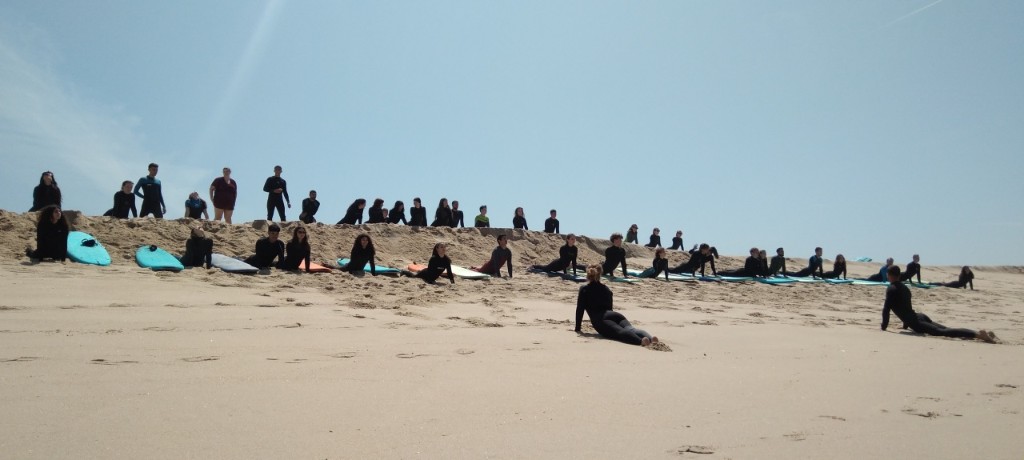 Large group stretching on the sand with boards — group surf lesson Aguda beach near Porto