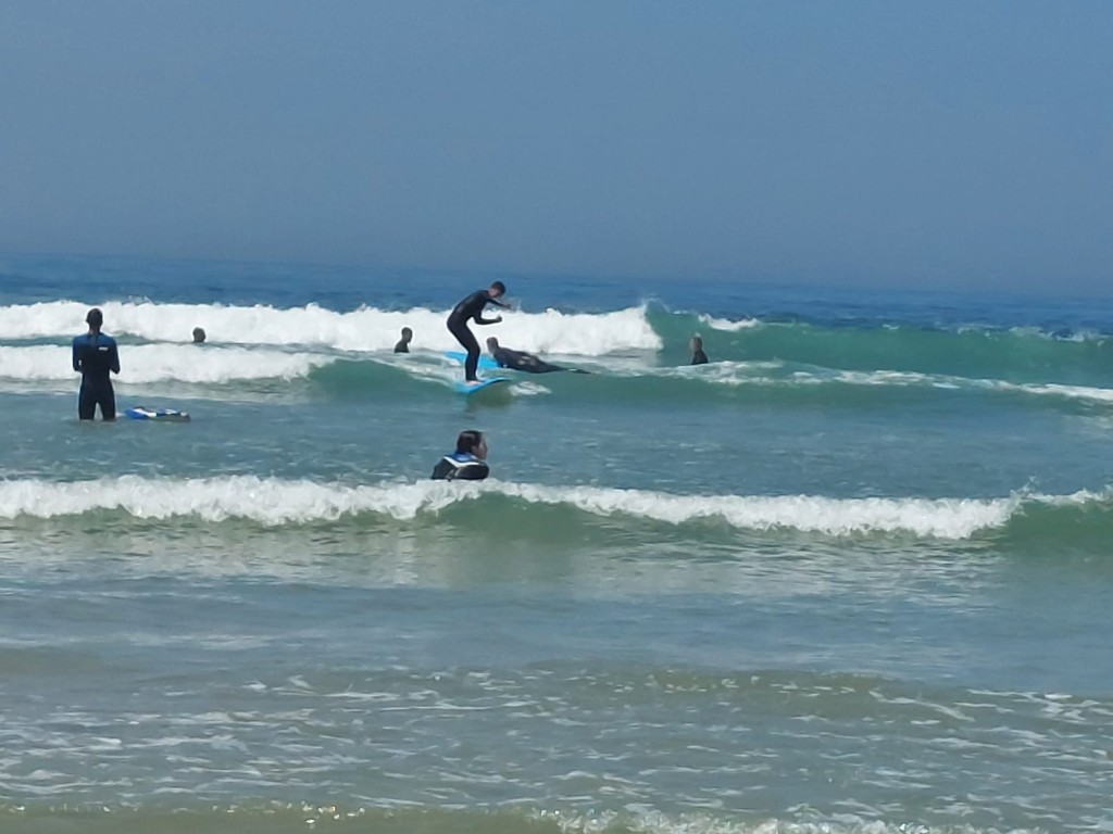 Group surf lesson in the water — rider on a blue board, surf Espinho and Aguda coast, Portugal