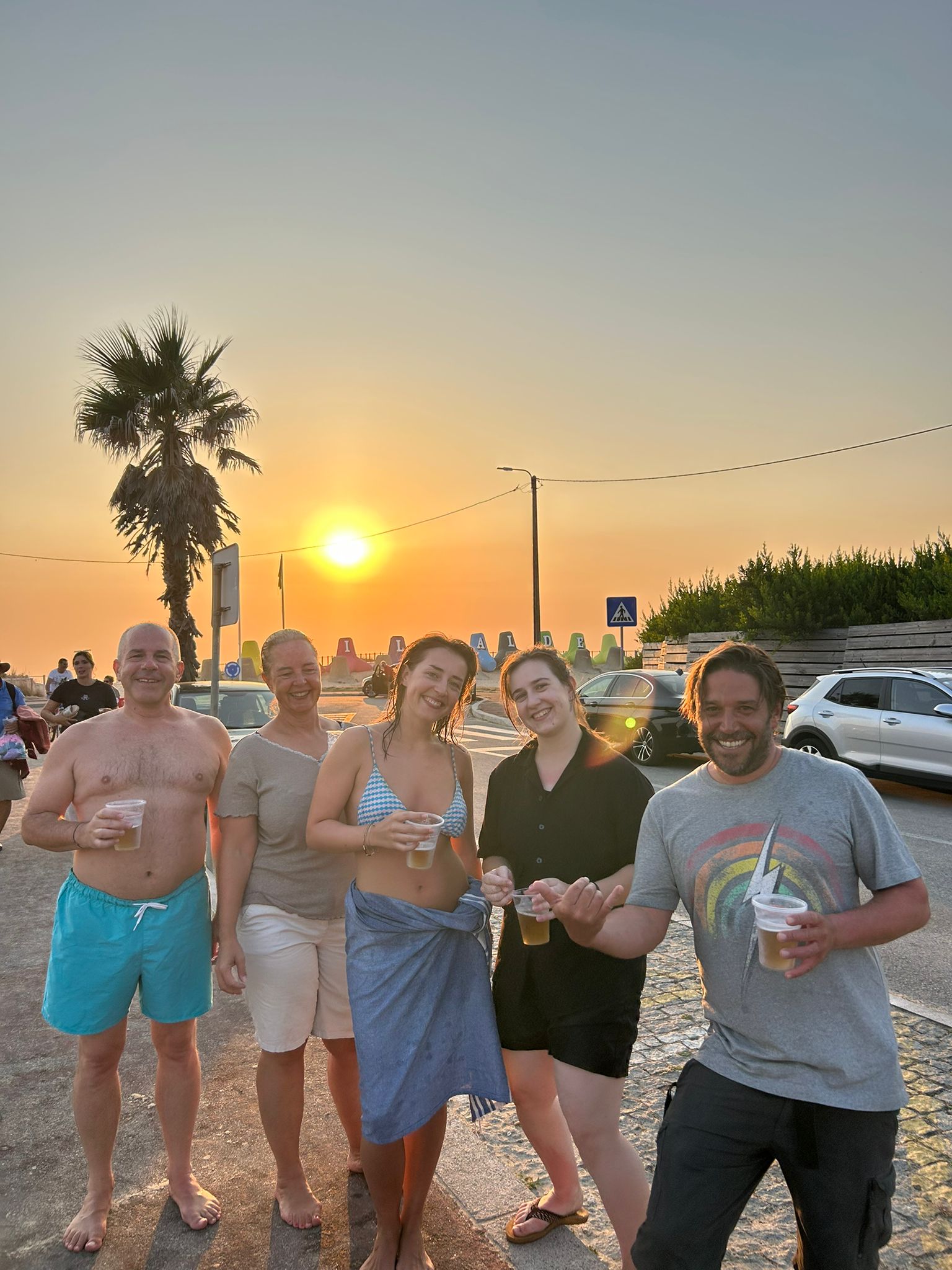 Group at sunset with drinks by the beach — surf Porto and Gaia lifestyle after lessons